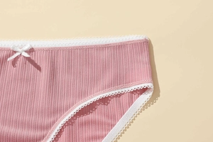 Detail of pink ribbed polyester panties with white lace trim and bow knot decoration
