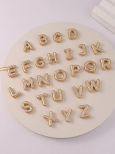 Macro view showing 26 gold balloon letter pendants with sparkling micro-pave cubic zirconia