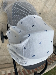 Detail of breathable muslin stroller cover with blue whale pattern in outdoor use