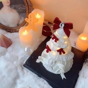 Detailed view of white Christmas tree ornament with red bows and warm LED string lights