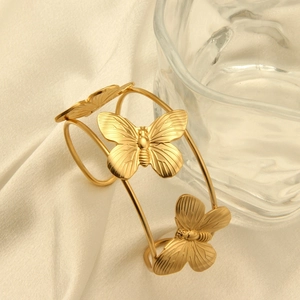 Macro shot of 18k gold plated stainless steel butterfly cuff bracelet on silk fabric