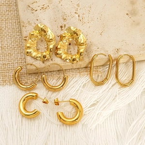 Set of four minimalist gold-plated irregular and geometric hoop earrings on travertine