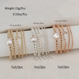 Detail of bohemian gold-filled beaded bracelets with baroque pearls and love charms