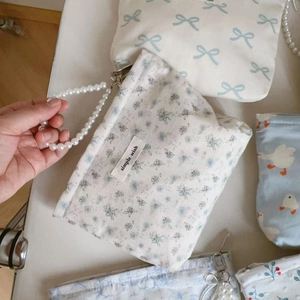 Detail of floral fabric pouch featuring elegant pearl handle and simple wish label