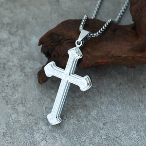 Macro shot of silver stainless steel cross pendant with engraved Lord's Prayer text