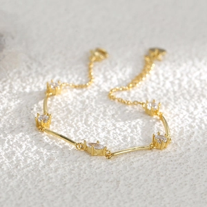 Gold plated brass bracelet with marquise cut zircon stones on textured white stone
