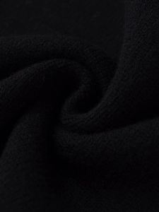 Macro view of black crewneck knit sweater fabric showing soft texture and tight weave