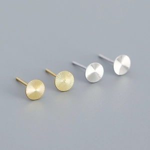 Macro shot of gold and silver S925 sterling silver stud earrings with CNC radial textures
