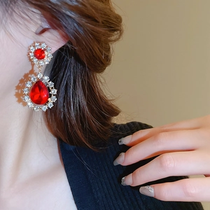 Détail de boucles d'oreilles vintage rouges avec cristaux et finition dorée sur modèle