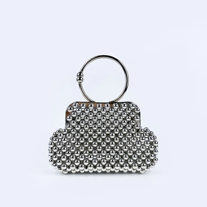 Detail of silver beaded handbag featuring a metal ring handle and ball clasp closure