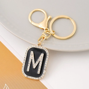 Letter M keychain with gold metal plating, black enamel, and sparkling rhinestone inlay