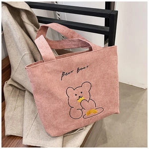 Detail of pink corduroy tote bag showing cute cartoon bear embroidery and soft texture