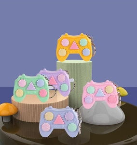 Mini game controller keychains in five colors displayed on artistic decorative props