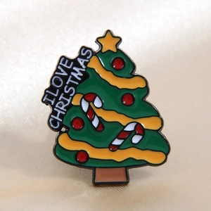 Green enamel Christmas tree pin with I LOVE CHRISTMAS text on gold satin fabric