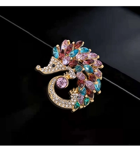 Macro shot of colorful rhinestone hedgehog brooch with gold plating on black background