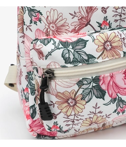 Close-up of floral daisy print and front zipper pocket on white canvas backpack