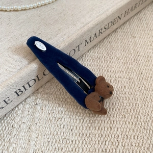 Detail of dark blue velvet hair clip with brown flocked bear and silver Love charm