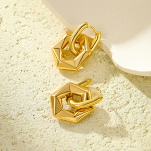 Minimalist golden stainless steel hexagonal earrings displayed on a white geometric block