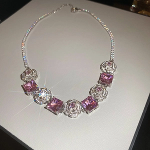 Detail of silver necklace with pink square stones and white flower patterns