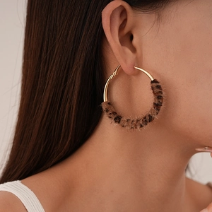 Detail view of large hoop earrings with gold metal and faux leopard fur textures