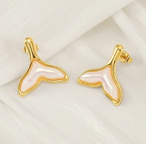Macro shot of 18K gold fish tail earrings with iridescent resin on white silk