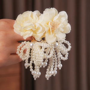 Detail of cream floral hair accessory with elegant white pearl tassels and soft fabric texture
