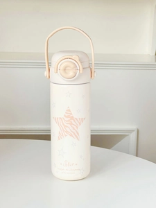 Close-up of beige insulated tumbler with star patterns and portable carrying loop