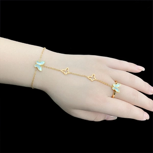 Bracelet bague papillon doré avec incrustations bleu clair sur une main de femme élégante