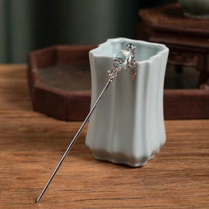 Detailed close-up of a crescent moon hair pin with star pendants on a ceramic holder