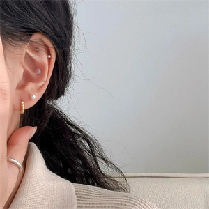 Detail of 925 sterling silver earring set with gold beads and a pearl on a model's ear