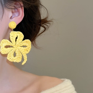 Macro detail of yellow handmade woven raffia flower earrings for summer vacation style
