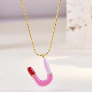 Detail of U-shaped enamel necklace in pink and white on golden chain over stone
