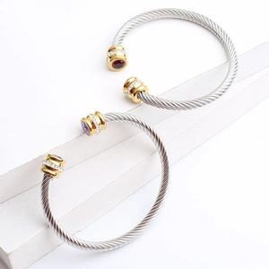 Detail of twisted cable bangles in silver and gold with red and purple gemstones