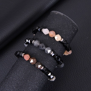 Close-up of three faceted agate stone stretch bracelets on a black jewelry stand