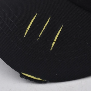 Gros plan des rayures brodées jaunes et bord usé sur une casquette de baseball noire