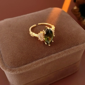 Dettaglio macro anello dorato regolabile con pietra verde e zirconi in astuccio marrone