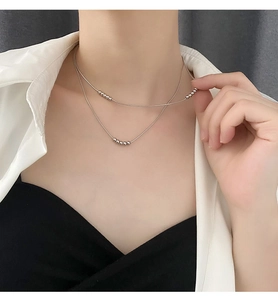 Close-up of minimalist silver double-layer beaded snake chain necklace on neck