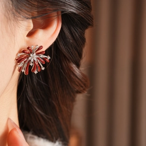 Détail de boucles d'oreilles fleurs avec pétales rouges et pierres de zircone cubique