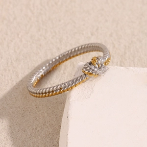 Detailed view of two-tone twisted rope ring hanging on a white stone display stand