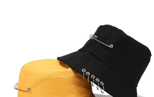 Détail de chapeaux bob noir et jaune avec anneaux métalliques et épingle de sûreté