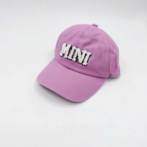 Detailed close-up of white fuzzy MINI embroidery on a lavender cotton baseball cap