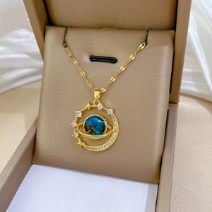 Detail of gold necklace featuring blue planet pendant and sparkling gems in a jewelry box