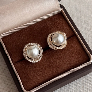 Elegant gold spiral earrings with white pearl and sparkling zircon in a jewelry box