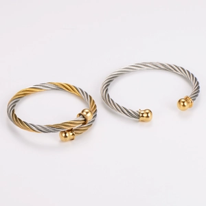Two-tone stainless steel cable twist bracelet with golden ball ends on white background