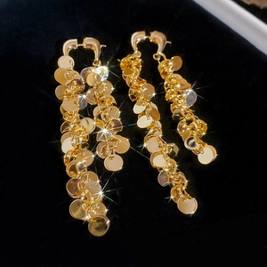 Vue détaillée des boucles d'oreilles à pompons ronds dorés sur fond de velours noir