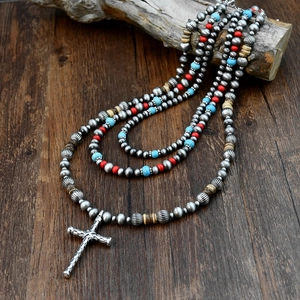 Detailed macro view of ethnic beaded necklace with turquoise and silver cross pendant