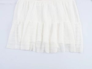 Detail of white mesh dress hem showing layered pleated lace texture and airy fabric
