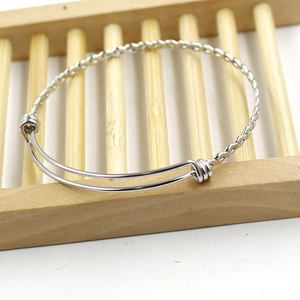 Detailed close-up of adjustable stainless steel twisted wire bracelet on wooden stand