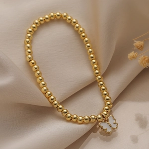 Elegant gold beaded bracelet with butterfly pendant on beige satin background