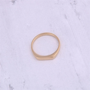 Macro view of a minimalist 18K gold plated rectangular geometric ring on marble